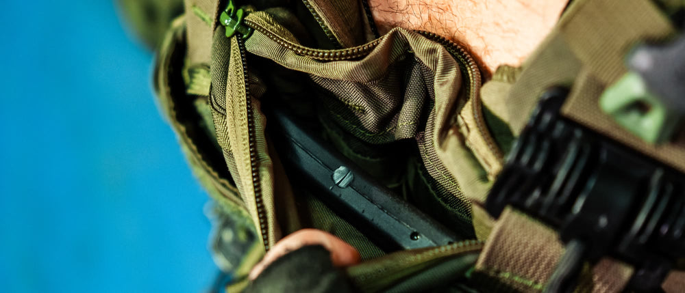 Gloved hands sliding an armor plate into a plate carrier