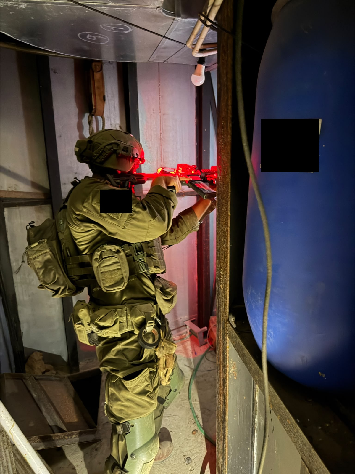 לוחם עם אפוד וציוד נשיאה ליד פתח במבנה